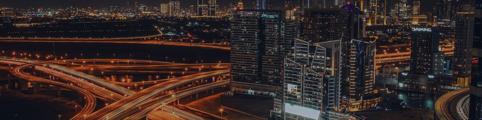 Dubai skyline at night with illuminated towers and sweeping highway interchanges